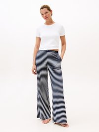 Top corto bianco a maniche corte con pantaloni larghi a righe navy e bianche dotati di tasche e cintura con marchio. Tessuto morbido, vestibilità rilassata.