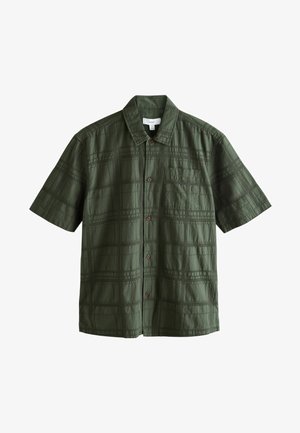 Camicia a maniche corte con bottoni in verde scuro, caratterizzata da un motivo a quadri testurizzato, collo a punta e tasca sul petto con bottoni marroni.