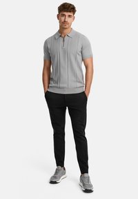 Gray short-sleeve polo with zipper, features vertical ribbing and a fitted design. Paired with black tapered pants and gray sneakers.