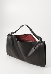 Black leather handbag with a shoulder strap and zipper, open to reveal a dark red fabric-lined interior with an inner zippered pocket.