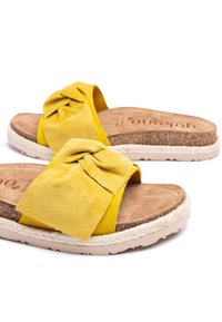 Gelbe Wildleder-Sandalen mit einem geknoteten Detail am Riemen, Korkfußbett und strukturierter weißer Gummisohle.