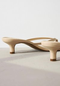 Sandales à talons nues au design minimaliste, avec des fines brides et un talon légèrement effilé. Texture lisse avec une finition mate.