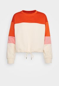 Dlouhý crop top s barevnými bloky v oranžové, krémové a růžové barvě, s kulatým výstřihem a regulovatelným stahovacím lemem.