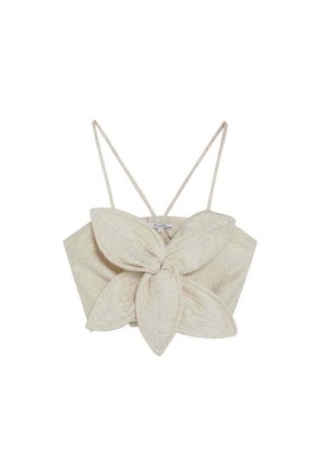 Top corto sin mangas de color beige con tirantes delgados y un gran lazo central en forma de pétalos en la parte delantera.
