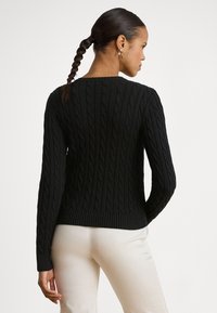 Μαύρο πουλόβερ με πλέξη καλωδίου, μακριά μανίκια, ριμπ μανσέτες και τελείωμα. Διαθέτει υφασμένο σχέδιο και στρογγυλή λαιμόκοψη.
