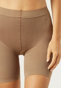 Pantalones cortos beige sin costuras, confeccionados con tejido elástico y un panel texturizado y transpirable en la cintura. Con bordes suaves y un diseño de longitud a medio muslo.
