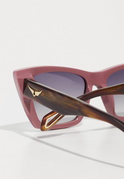Cat-eye sunglasses with a matte pink frame and gradient purple lenses. Tortoiseshell arms feature a gold accent with a wing design.