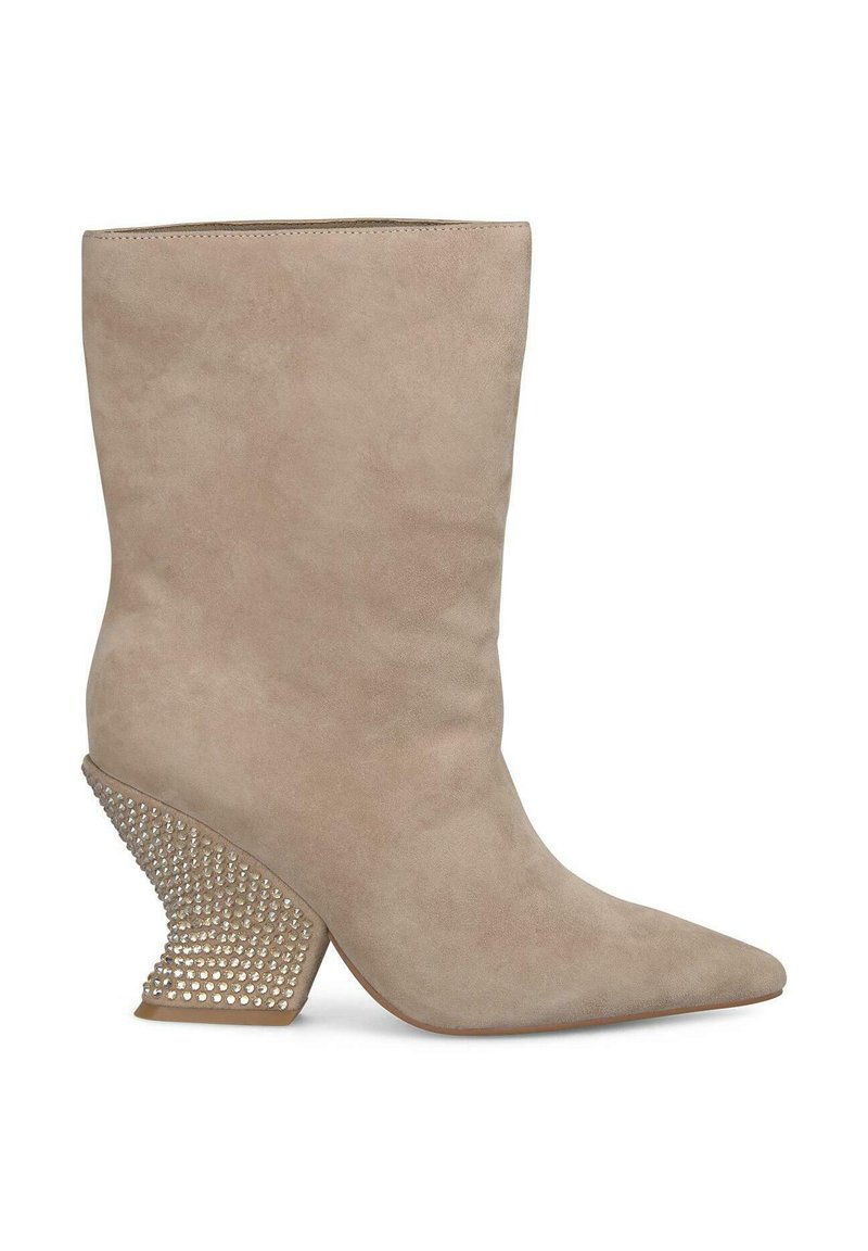 Bottine en daim beige avec un bout pointu et un talon texturé clouté s'élargissant vers l'extérieur, présentant une finition élégante et lisse.