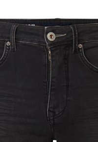 Jeans de mezclilla negra con una cintura alta, con cremallera y cierre de botón. Detalles de costura acentuada visibles en los bolsillos y las costuras.