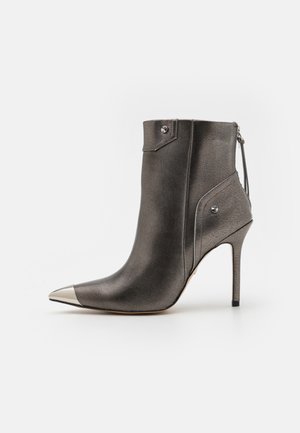 Stivaletto alla caviglia grigio metallico con punta a punta e cappuccio argento, dotato di zip e accenti decorativi sui lati. Tacco stiletto alto.