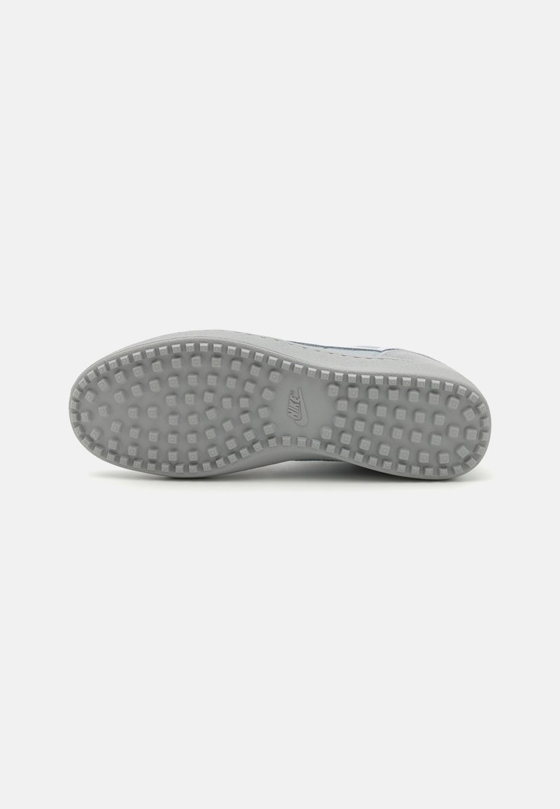 Grau Sport-Schuhsohle mit einer strukturierten Gummioberfläche und einem Rautenmuster für Trittfestigkeit, sowie einem eingravierten Logo in der Mitte.