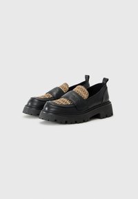 Black leather loafers with patterned brown fabric tops, featuring a chunky black sole and front strap accent. Slip-on design with back pull tab.