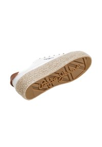 Hvite sneakers med en teksturert tan gummi ytre såle, med en vevd jute mellomsåle. Logoen er fremtredende plassert på bunnen og siden.