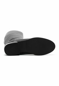 Bottes noires montantes en matériau lisse avec un nez arrondi et une semelle en caoutchouc texturé. La tige présente un design froncé.