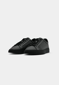Schwarze Sneaker aus glattem Leder und strukturiertem Stoff. Mit runder Zehenpartie, Schnürdesign und flacher Gummisohle.