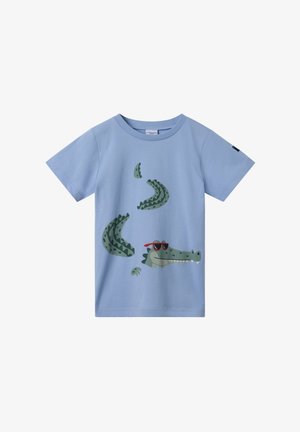 Lys blå bomulds T-shirt med et grønt krokodillegrafik iført røde solbriller, med mønstrede skæl og rund halsudskæring.