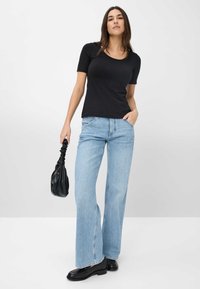 Sort kortærmet t-shirt parret med lyseblå vide jeans, der komplementeres af en sort skuldertaske og ankelstøvler. En simpel og afslappet stil.