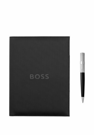 Czarny teksturowany notatnik z wytłoczonym logo „BOSS” oraz srebrno-czarny długopis umieszczony po jego prawej stronie, przedstawione na białym tle.