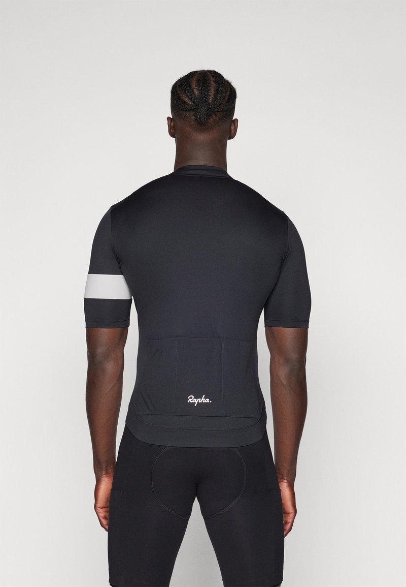 Jersey de ciclismo de manga corta en tela negra, con una franja reflectante gris en la manga y un bolsillo trasero texturizado con el logo de la marca.