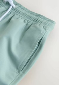 heleheledad lühikesed püksid, mis on valmistatud pehmest kangast, varustatud elastse vöökohaga, millel on pael ja küljetaskud. Sile tekstuur ja lihtne disain.