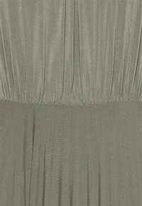 Ljusgrön klänning med en samlad överdel och en svävande kjol. Tillverkad av mjukt material med en subtil glans och vertikala veckdetaljer.