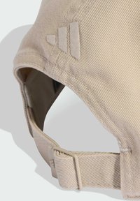 Gorra beige con un tejido texturado y acanalado. Presenta una correa trasera sólida y un acento de logo en el costado. Diseño minimalista con visor curvado.