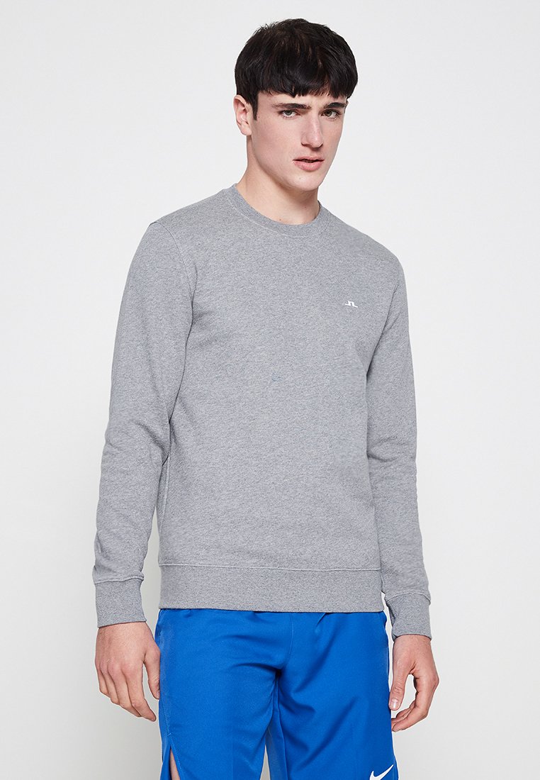 Grå crewneck sweatshirt gjord av en bomullsblandning, med långa ärmar och ribbad nederkant. Litet vitt logo på bröstet, utan mönster eller detaljer.