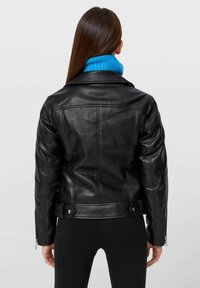 Mustat nahkatakki, jossa on istuva muotoilu, vyövyötärö, vetoketjuhihansuut ja takaselän venttiili, yhdistettynä kirkkaan siniseen ribattyyn kaulukseen.