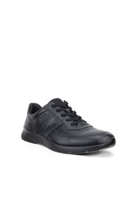 Zwarte leren vetersneaker met gevoerde kraag, gestructureerde zool en subtiele zijstiksels op een witte achtergrond.