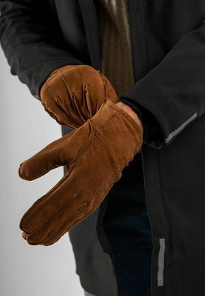 Bruine suède handschoenen met een ontspannen pasvorm, met een opvallend geplooid ontwerp bij de pols en stiksel details, gedragen door een persoon.