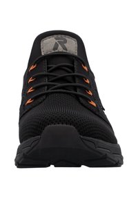 Chaussure de sport noire avec tige en mesh, lacets noirs passant dans des œillets orange, et écusson de marque sur la languette.