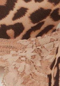 Tissu à motif léopard avec des tons marron et beige clair, associé à une garniture en dentelle pêche avec un bord festonné et des motifs complexes.