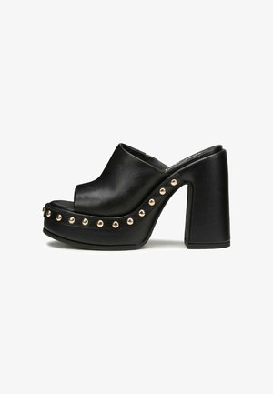 Mule open-toe in pelle nera con piattaforma e tacco a blocco alto, caratterizzate da borchie dorate lungo il lato e una trama liscia.