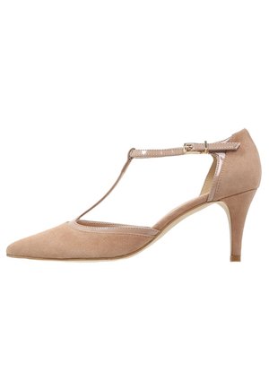 Beżowe zamszowe szpilki na pasku w kształcie litery T z zaostrzonym noskiem, cienkim paskiem na kostkę i smukłym obcasem. Posiadają przeszywany wzór oraz błyszczący akcent na pasku.