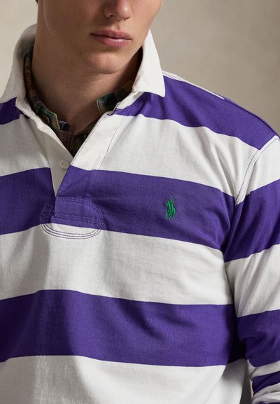Lila-fehér csíkos rugby póló gallérral, bal mellkason kis zöld hímzett logóval. Puha pamut anyag.