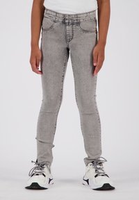 Jeans grises de corte ajustado y textura deslavada. Con diseño de cinco bolsillos y cinturilla cosida. Combinados con zapatillas blancas y negras.