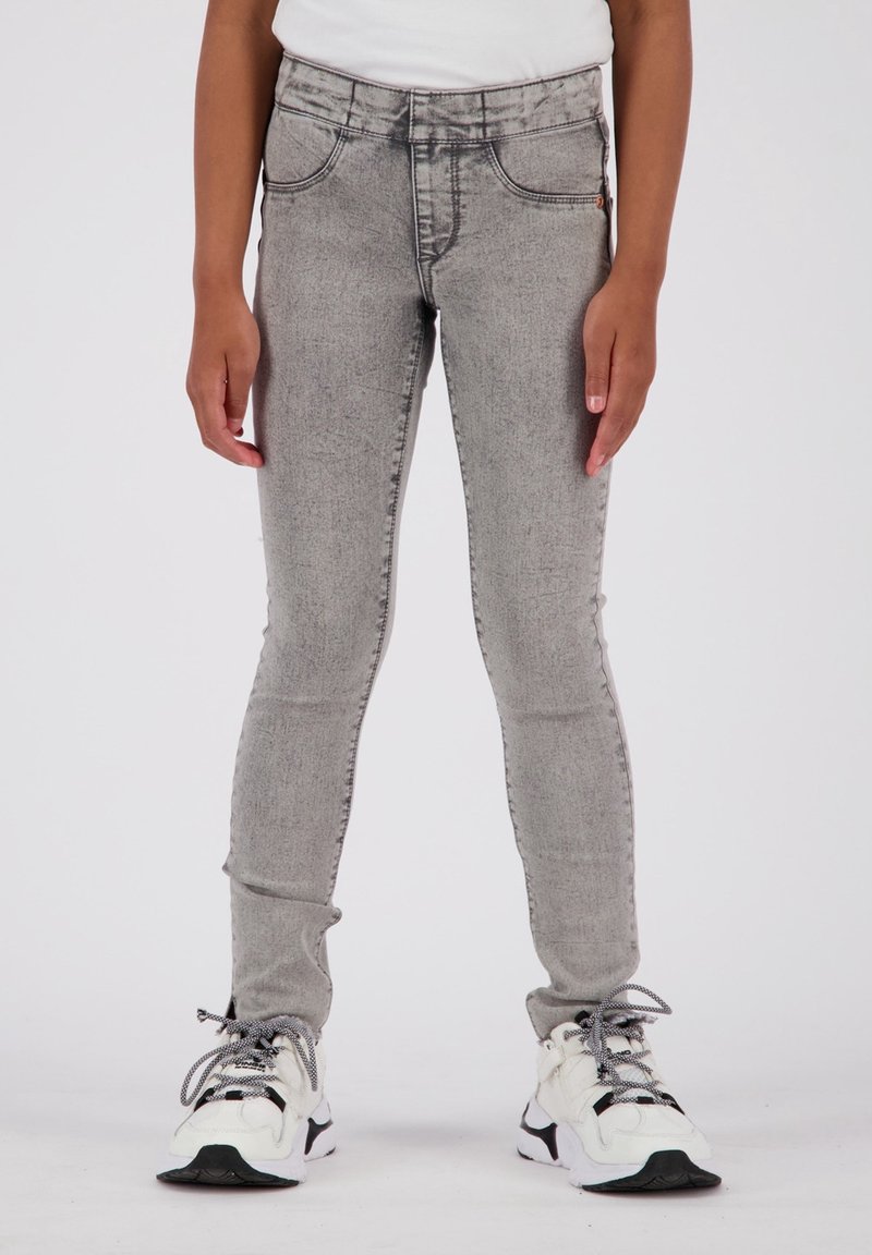 Jeans grises de corte ajustado y textura deslavada. Con diseño de cinco bolsillos y cinturilla cosida. Combinados con zapatillas blancas y negras.