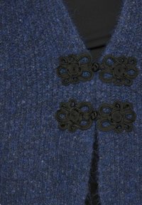Tengerészkék kötött kardigán, texturált felülettel; elöl két fekete dekoratív záróelemmel, virágmintával.