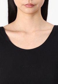 Czarny prążkowany top z dekoltem w serek i haftowanym logo "VOLCOM" na klatce piersiowej. Gładka tekstura materiału, dopasowany krój.