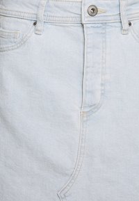Gonna di jeans azzurro chiaro con tasca frontale, passanti per la cintura e chiusura con bottone. Il tessuto è morbido al tatto e presenta dettagli di cucitura sottili.