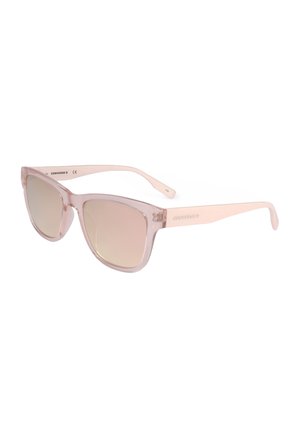 Occhiali da sole rosa chiaro traslucidi a forma di occhio di gatto con lenti marroni sfumate e aste sottili, con il marchio "Converse" sul lato.