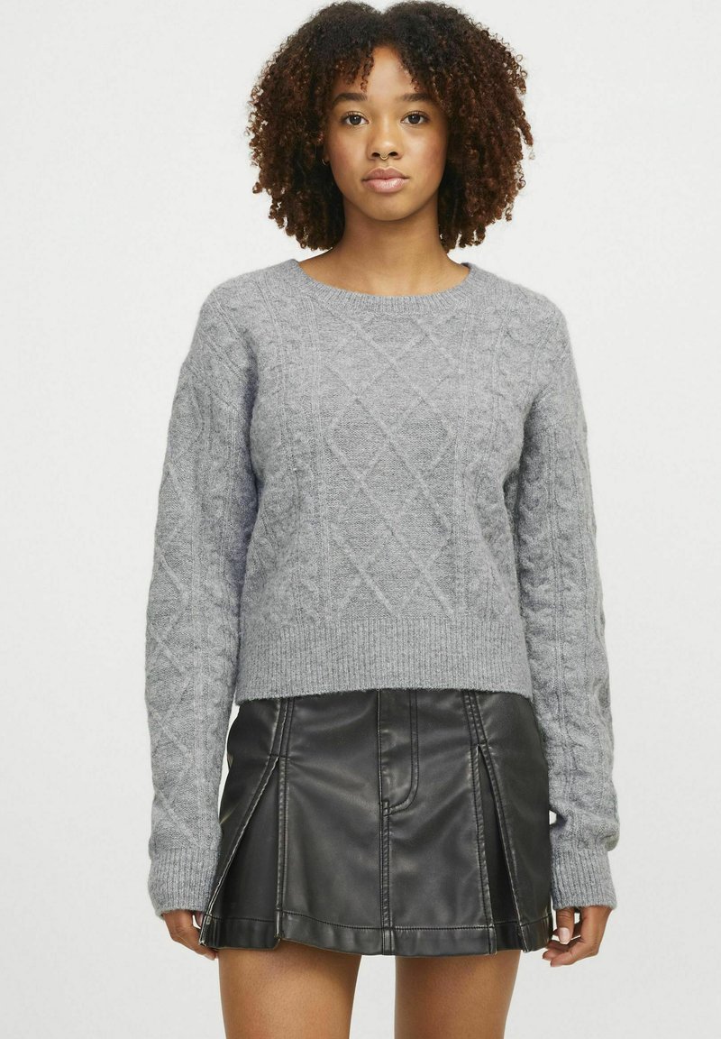 Maglione grigio a maglia con motivo a trecce, colonna rotonda e maniche lunghe, abbinato a una gonna nera in ecopelle.