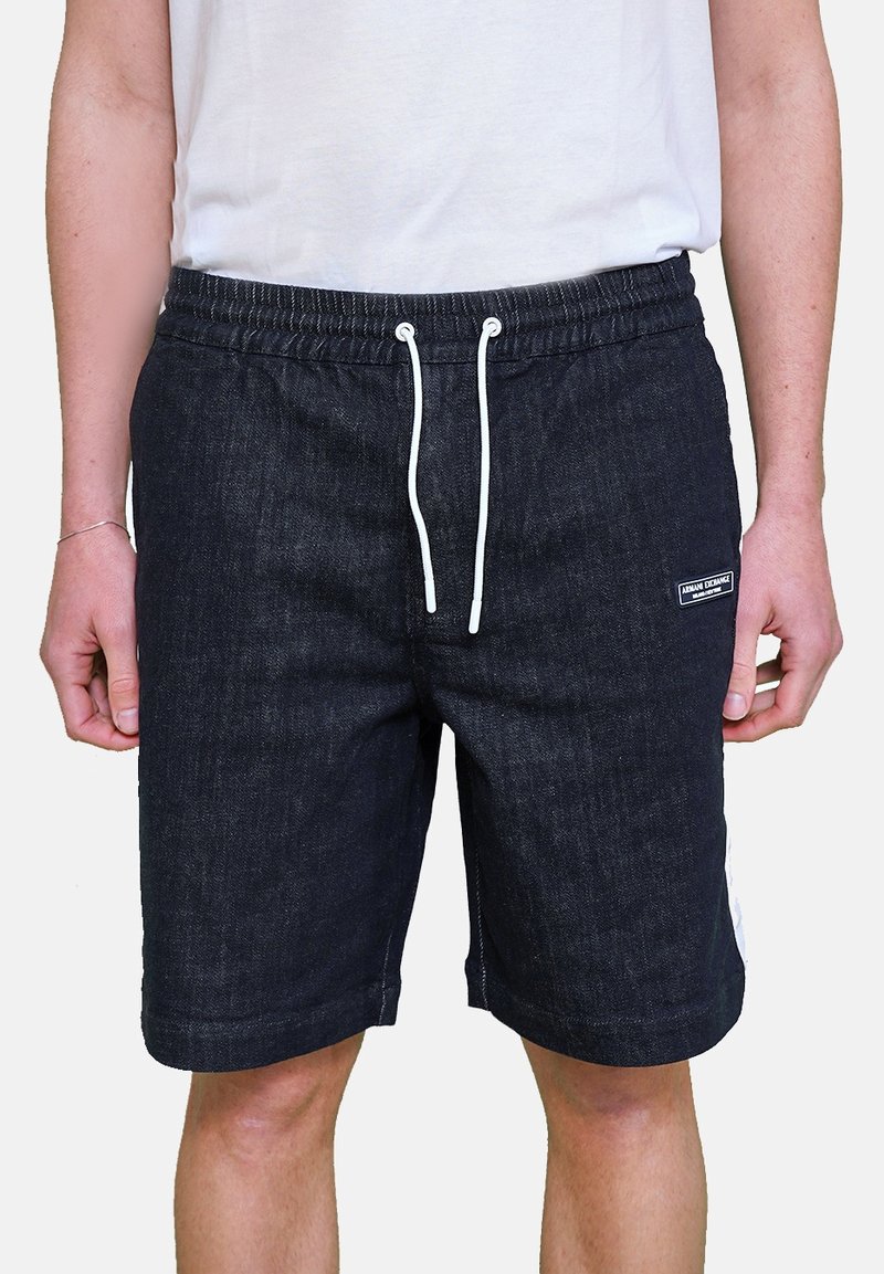 Shorts in denim scuro con vita elastica, coulisse bianca e tasche laterali. Presenta un piccolo etichetta del marchio sul lato sinistro anteriore.