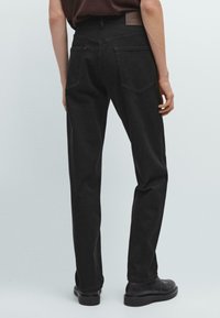 Zwarte spijkerbroeken van denim met een rechte snit, achterzakken en een leren label op de tailleband. Soepele textuur en minimale details.