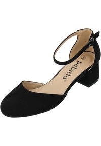 Zapato negro de ante con correa al tobillo, con una punta ligeramente redondeada, tacón de bloque de altura media y forro interior en color marrón. Detalle de hebilla ajustable.