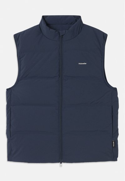 Marinblå vadderad väst med hög krage, dragkedjestängning och öppningar vid armarna. Har en liten logotyp på bröstet och en slät yta.