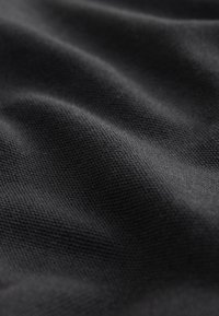 Must tekstuuriga kangas punutud mustriga, millel on pehmed voldid ja matt viimistlus.