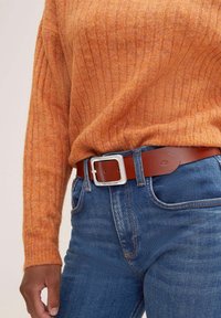 Ceinture en cuir marron avec une boucle rectangulaire en argent, portée sur un jean en denim bleu et un pull en coton côtelé orange. Design texturé et décontracté.