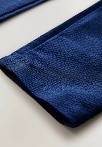 Granatowy tekstylia z teksturowanym, sześciokątnym wzorem, z czystym wykończeniem na krawędziach i gładką powierzchnią.