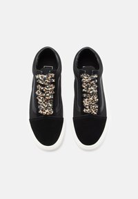 Black sneakers with a mix of suede and fabric, featuring a leopard print design on elastic laces and a white rubber sole.